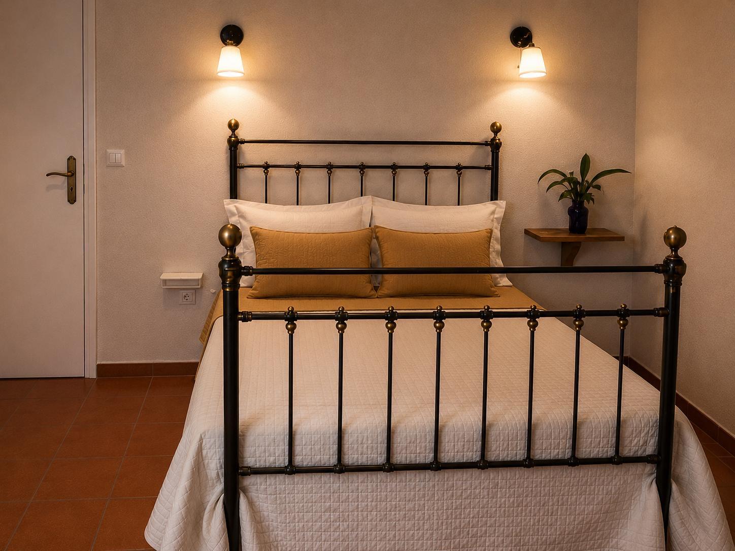 Quarto com cama de ferro forjado e apliques de parede
