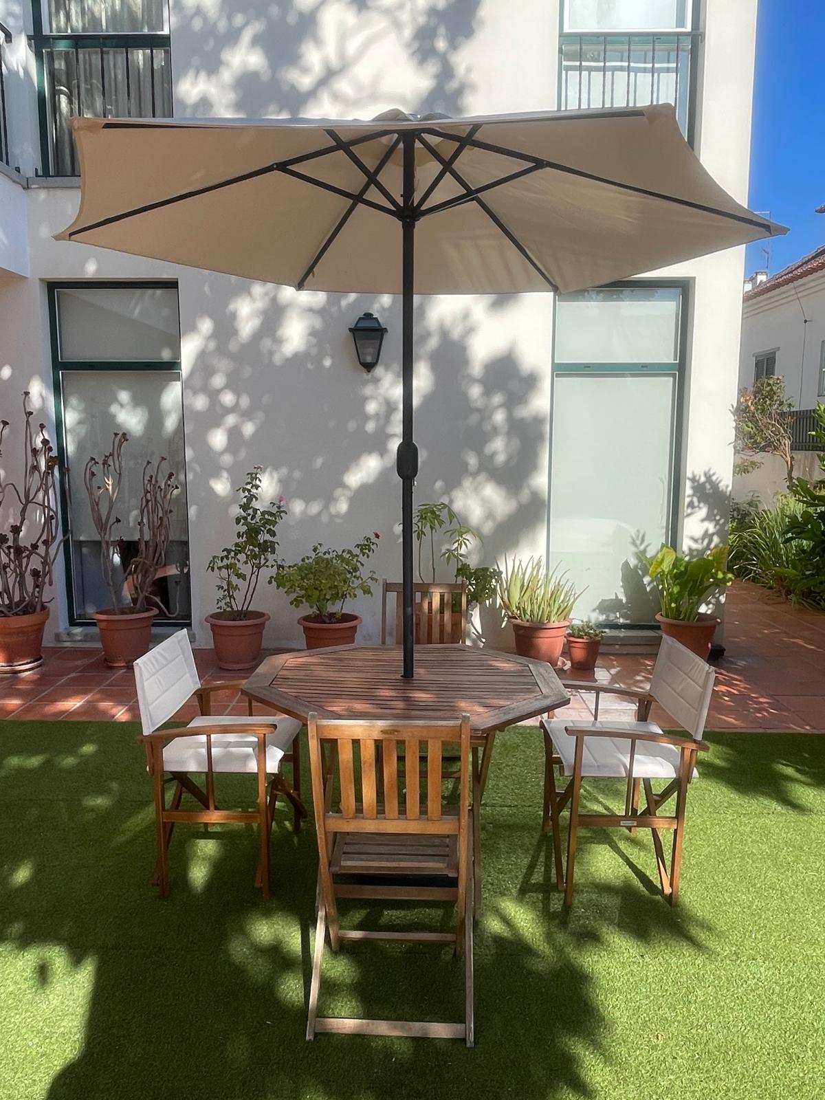 Pátio exterior privado da Vila JC com chapéu de sol
